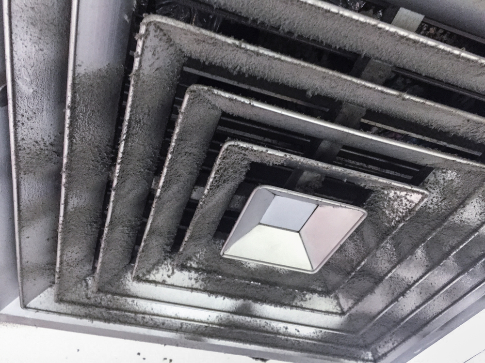 Technician performing professional air duct cleaning in a commercial building ventilation system