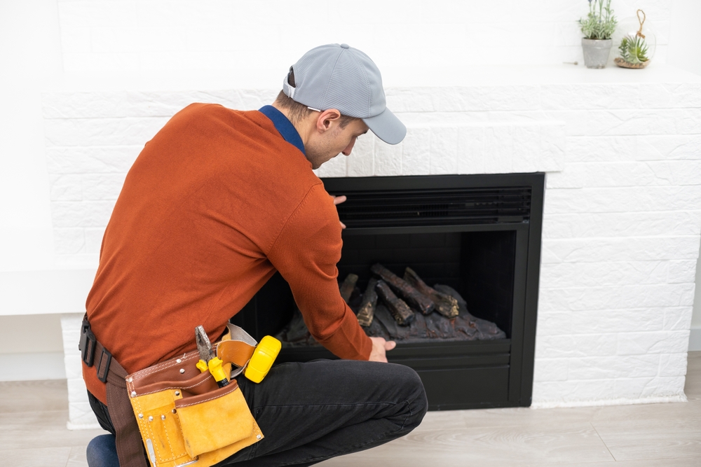 Professional technician explaining chimney cleaning costs while servicing a residential fireplace chimney