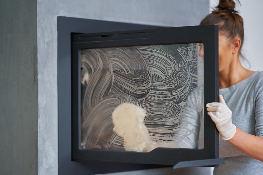 Homeowner performing wood-burning fireplace cleaning for safer and more efficient fireplace use